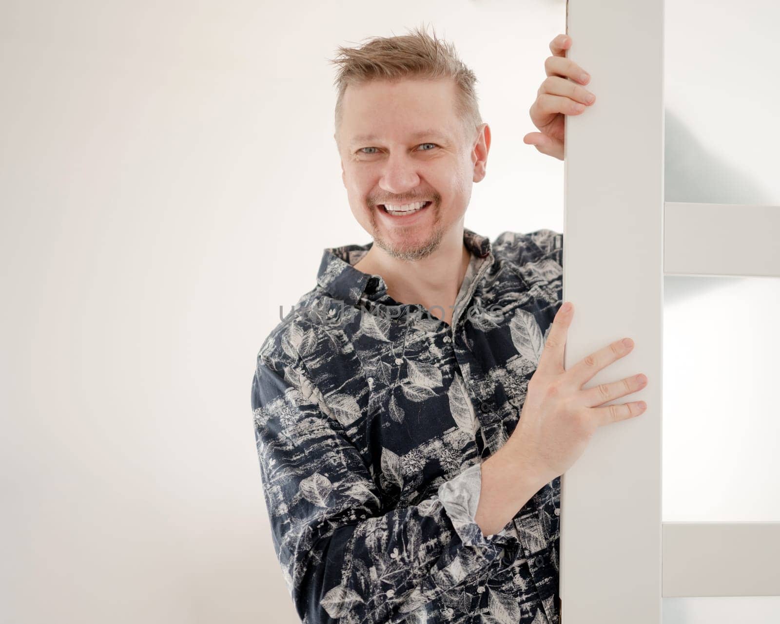 Happy Man Peeking Behind Door At Home