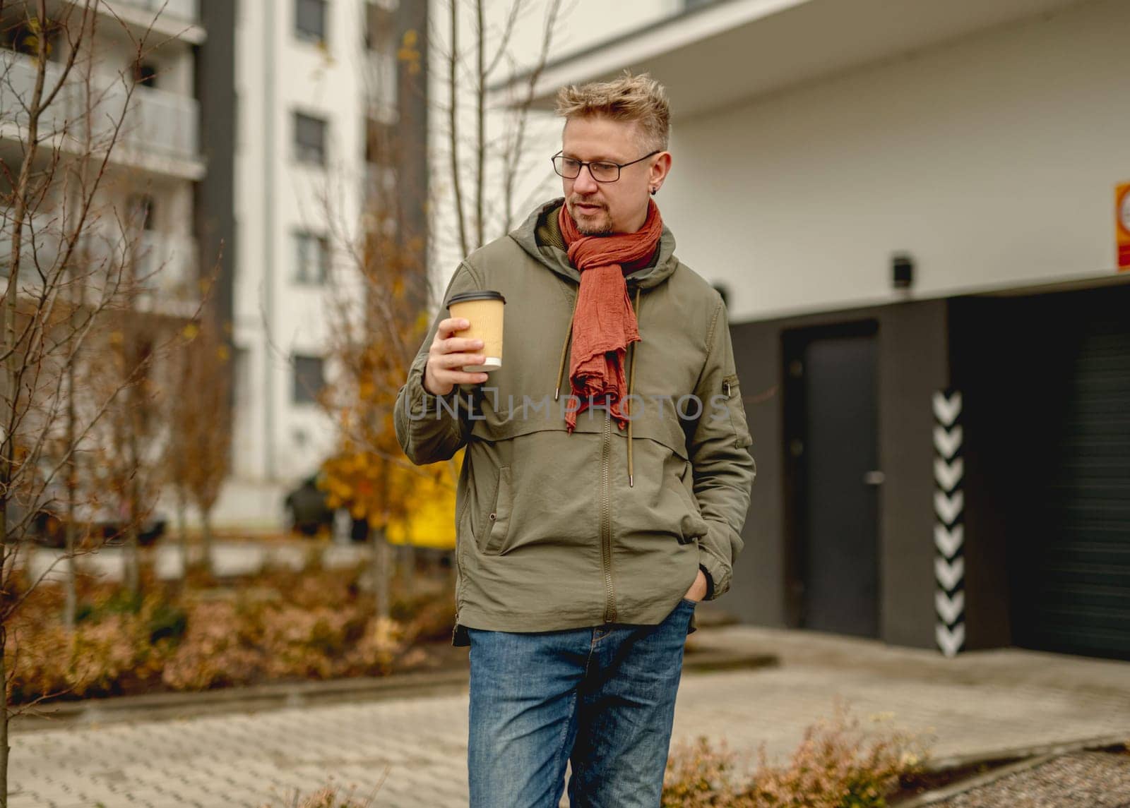 Young Attractive Man Stands On A Street Having Morning Coffee Near A Garage