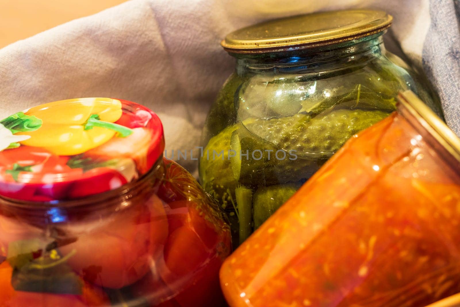 Jars with different types of pickles and preserves in a wicker basket. Food