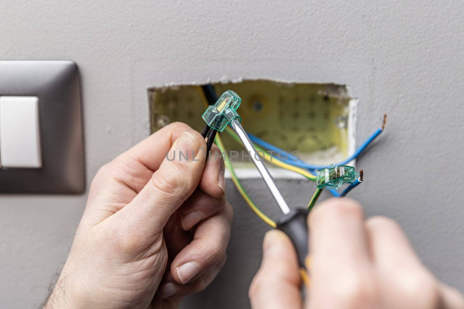 Electrician connecting wires using a connector block and screwdriver