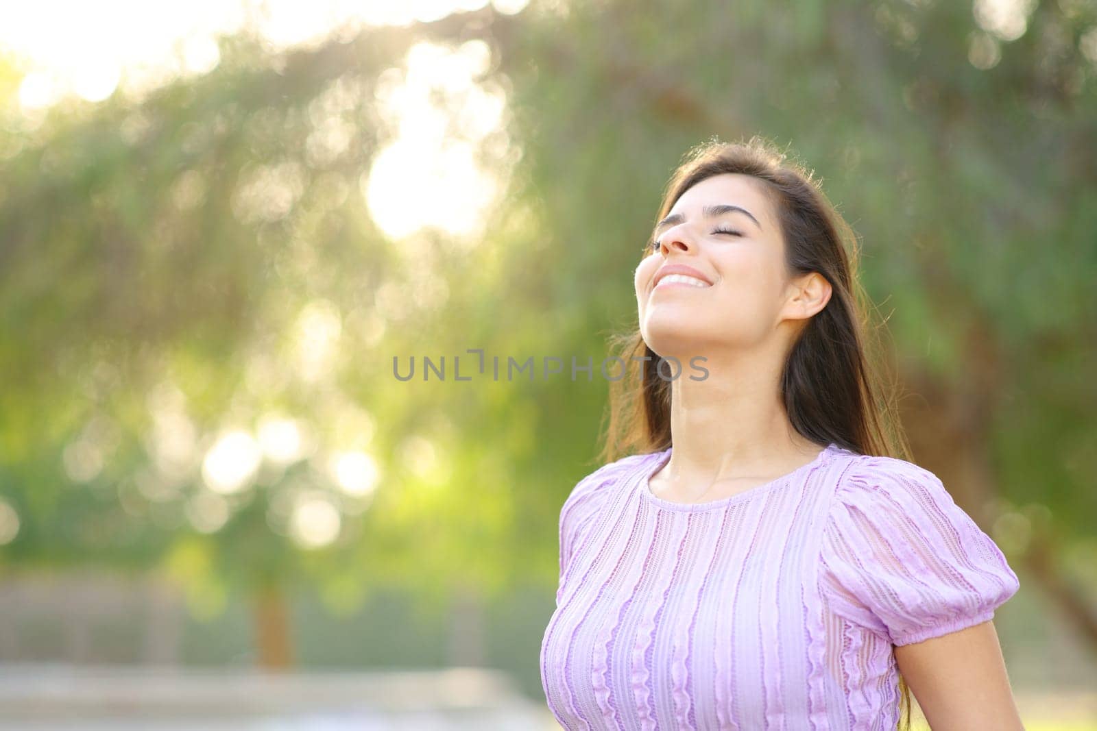 Happy woman breathing fresh air standing in a park