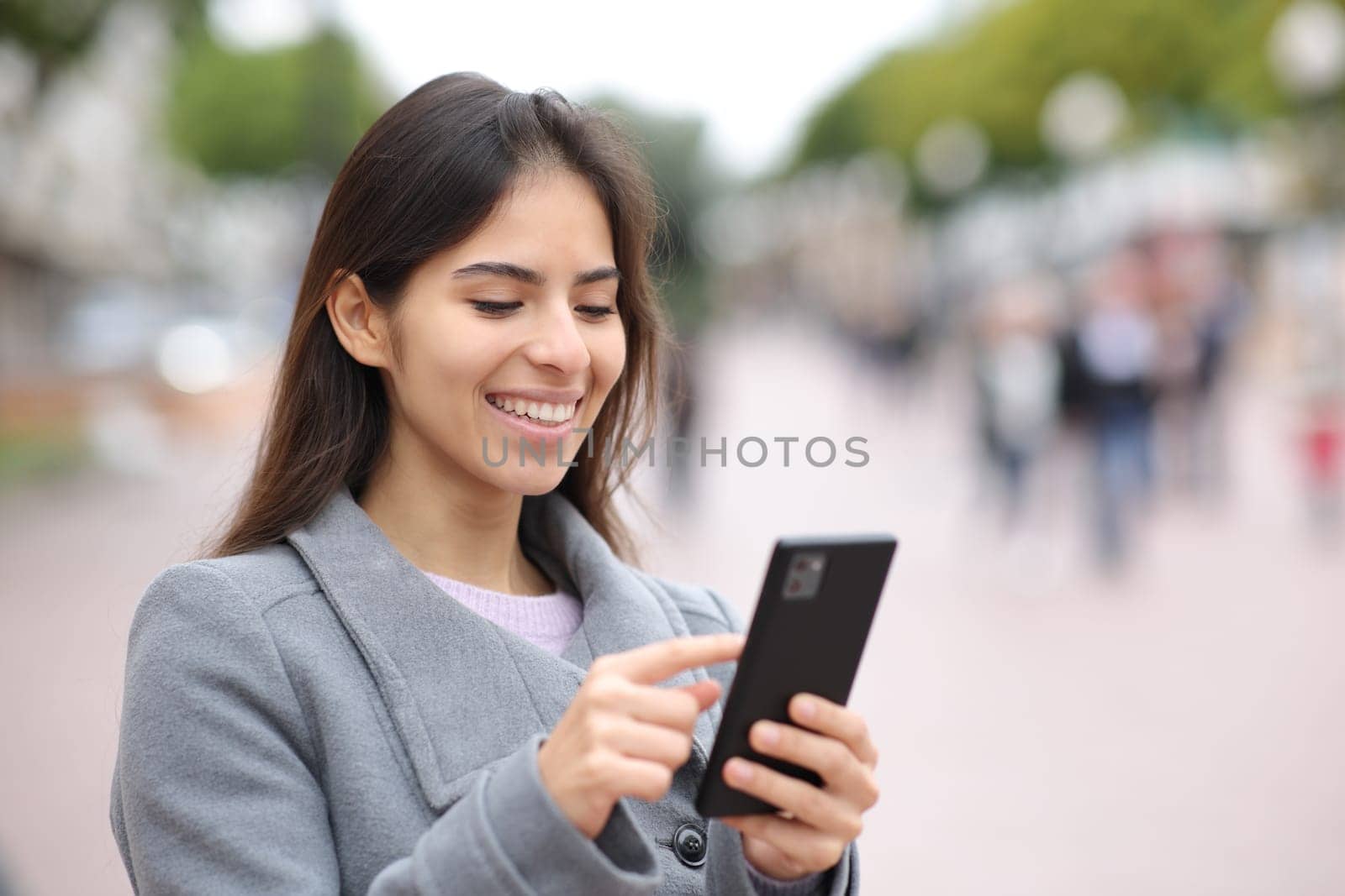 Woman using cell phone in street in winter