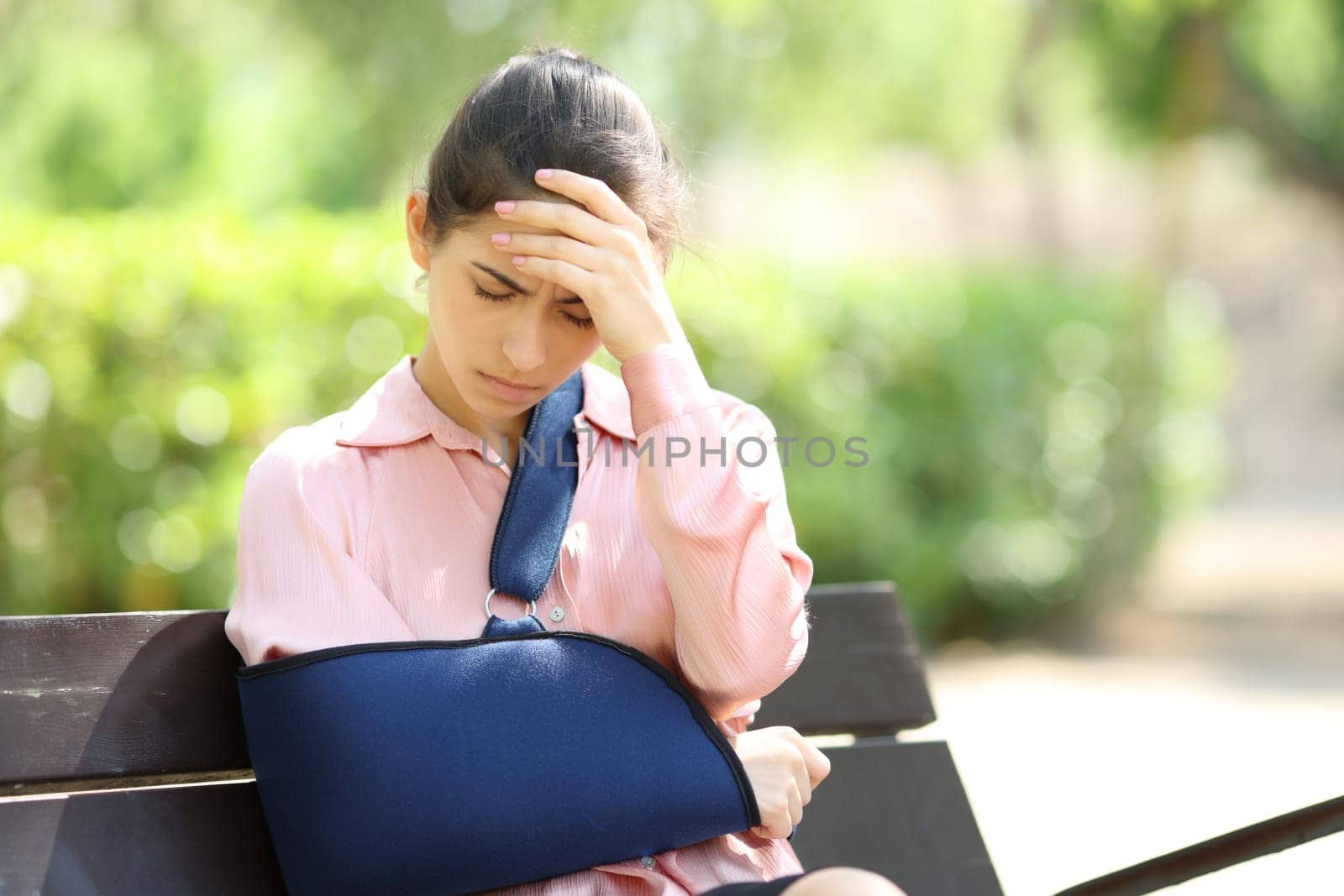 Worried convalescent woman sitting on a bench complaining in a park
