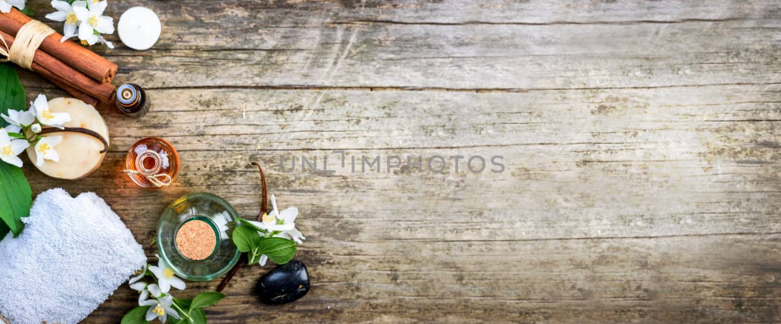 Top view of essential oils with jasmine, cinnamon and vanilla on rustic wooden table with copyspace. Spa and wellness aromatherapy treatment. Asian massage and skin care background design.