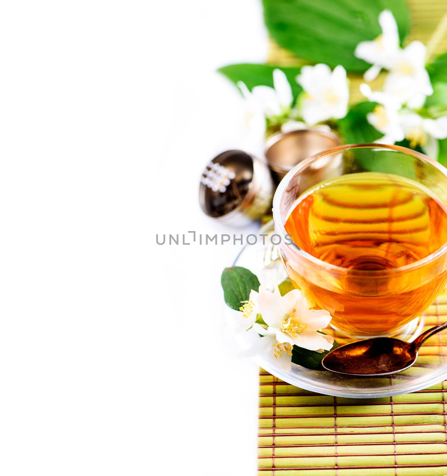 Herbal green tea with jasmine flower in transparent teacup border isolated on white background with cpyspace. Traditional asian hot beverage in glass cup. Organic healthy herbs for alternative medicine.