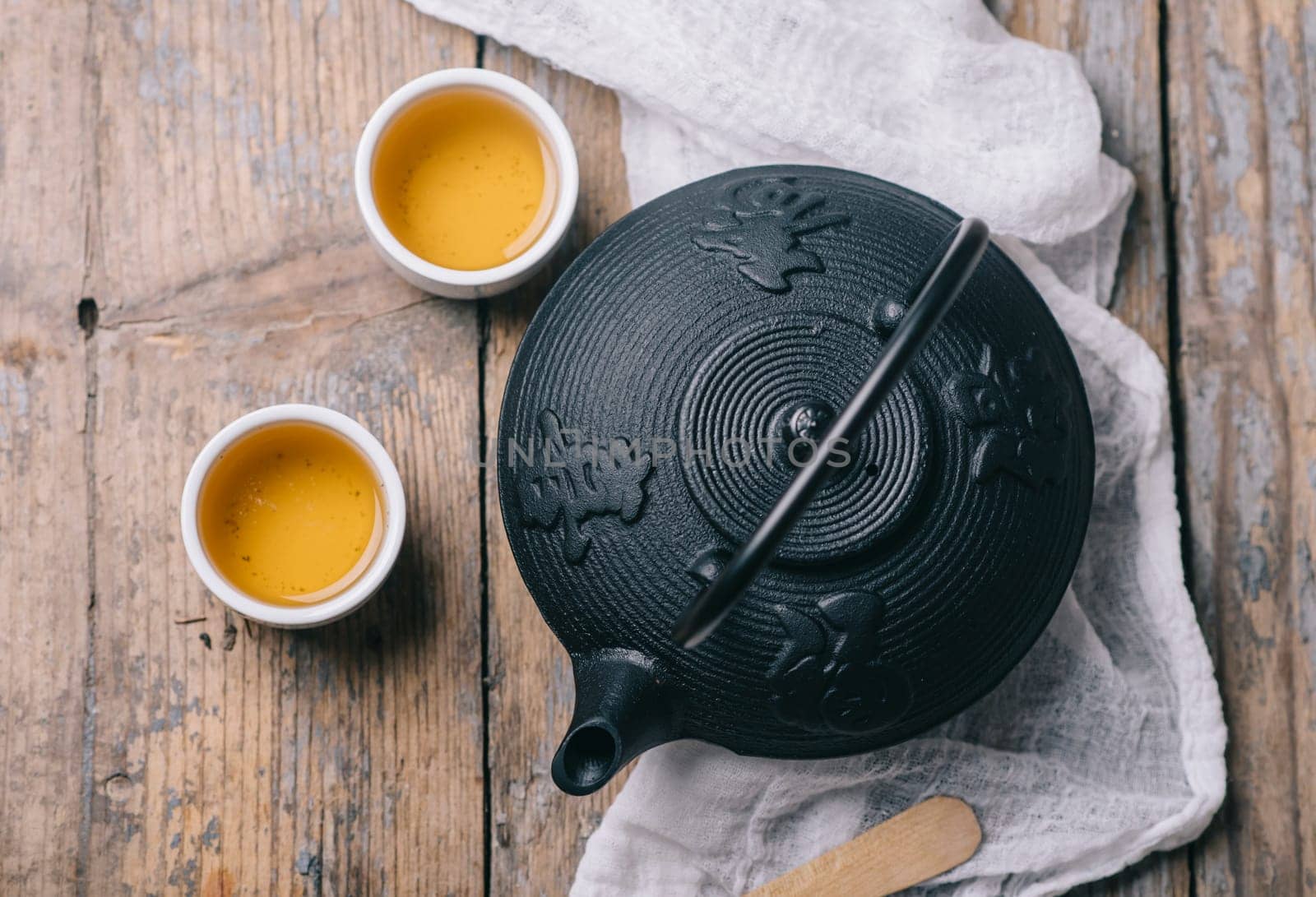 Traditional japanese herbal tea recipe prepared in cast iron teapot with organic dry herbs from above. Top view of asian traditional hot beverage on wooden table.