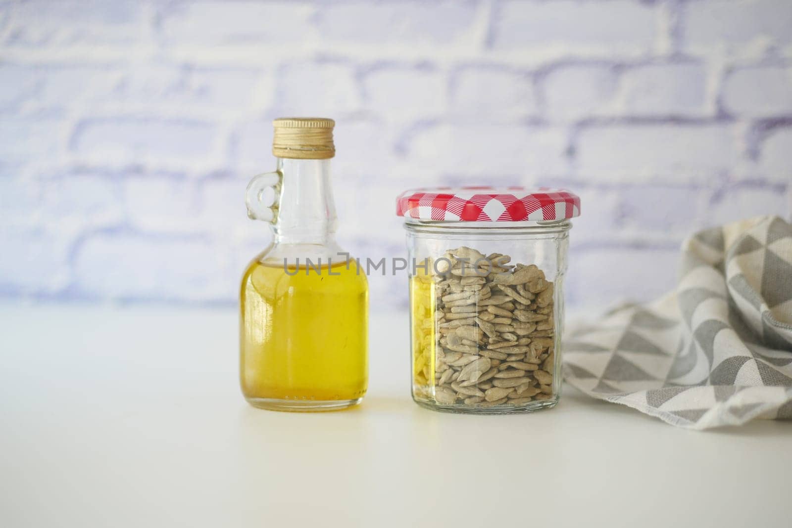 Glass jar filled with seeds and a bottle of oil on a kitchen counter