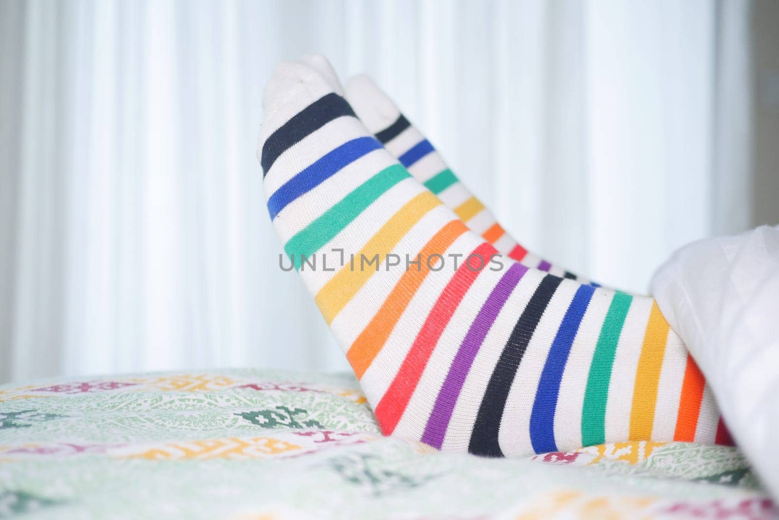 Vibrant, striped socks are laid out on a bed, creating a cozy vibe.