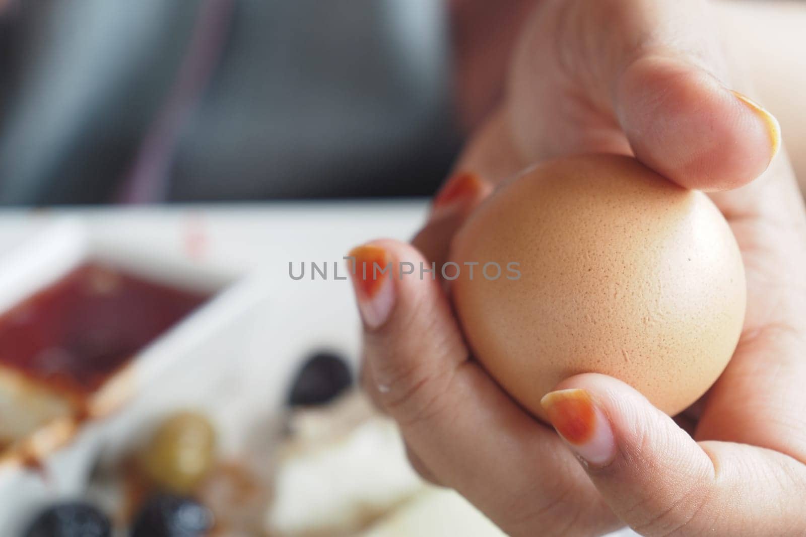 A person holds a brown egg with various culinary items nearby.