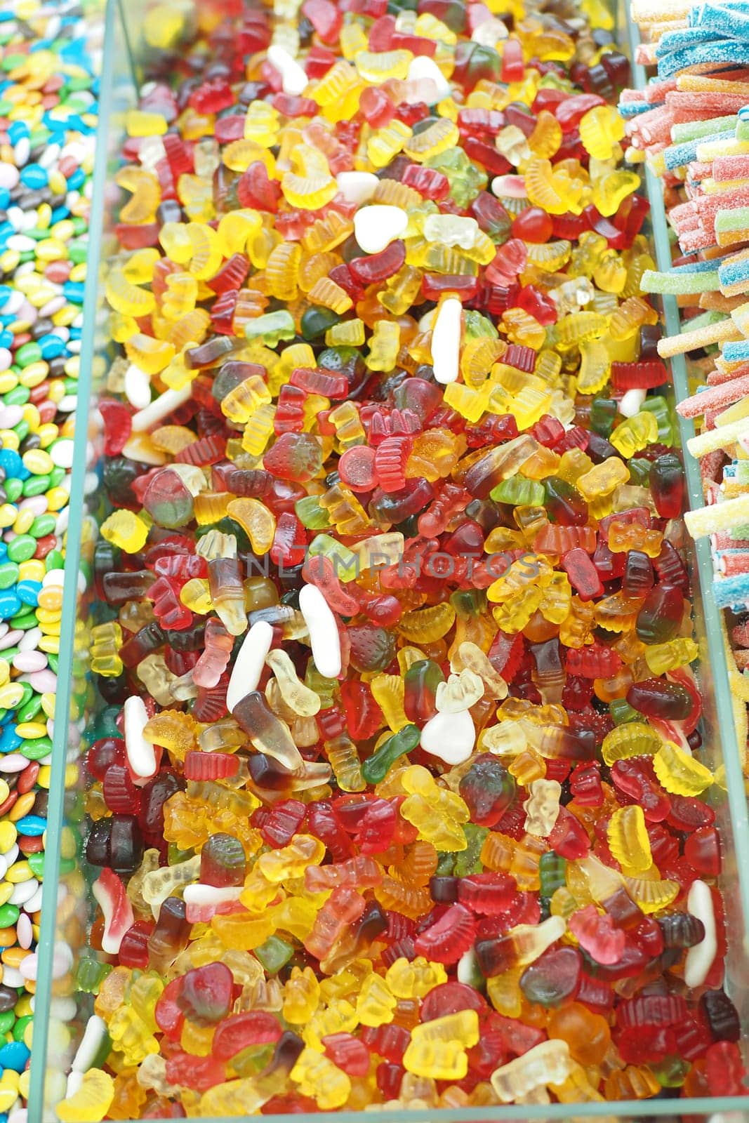 A vibrant mix of gummy candies fills a display case at a shop.