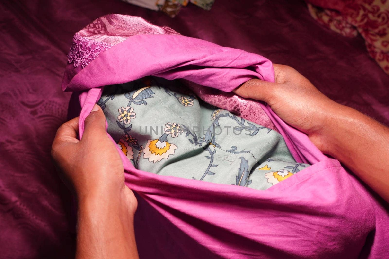 Hands carefully fold a pink fabric revealing a patterned interior.
