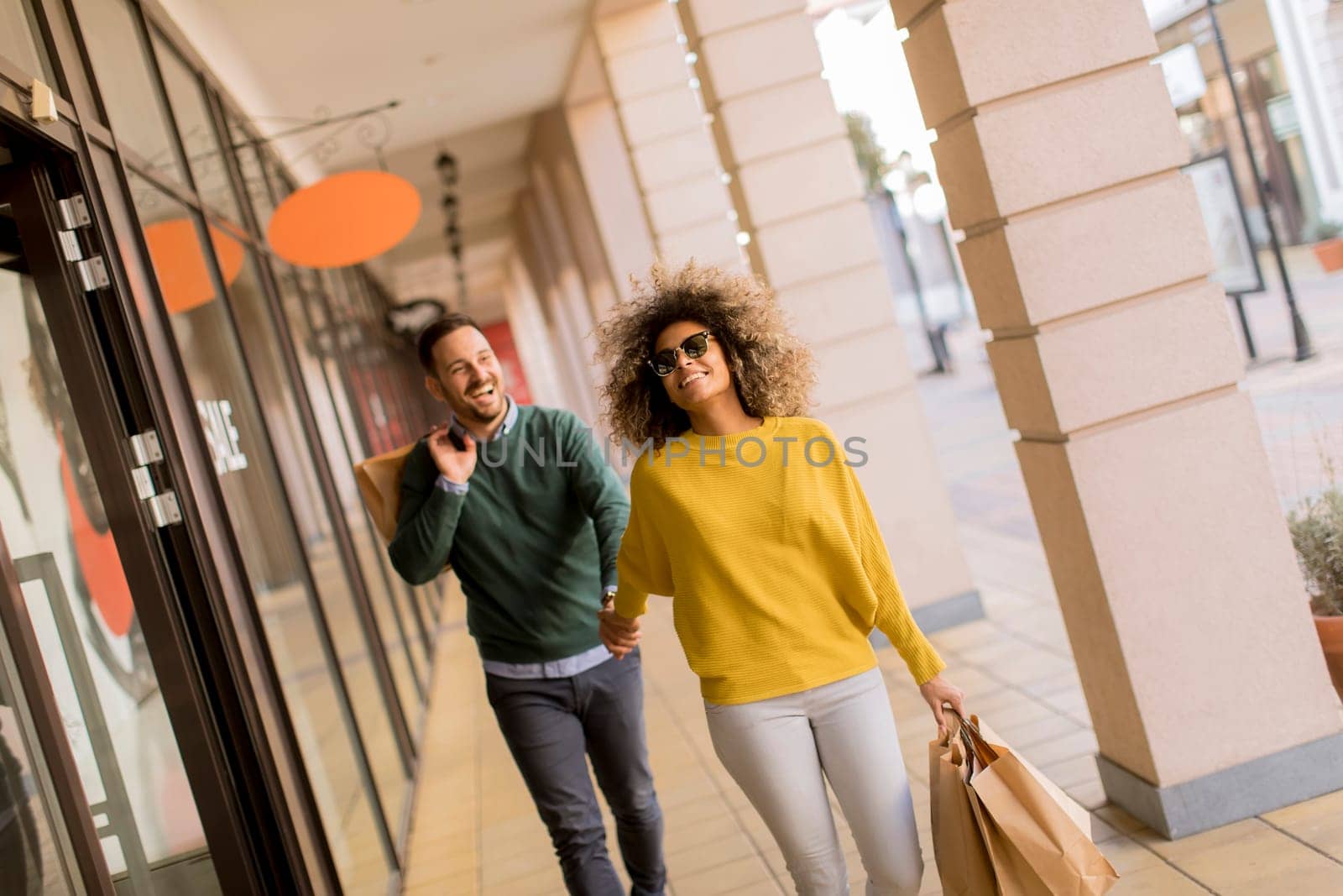 Beautiful young multiethnic couple with paper bags enjoying in shopping, having fun in the city