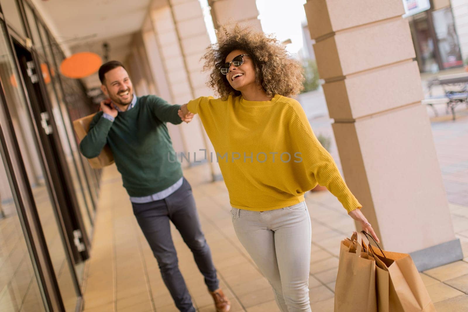 Beautiful young multiethnic couple with paper bags enjoying in shopping, having fun in the city