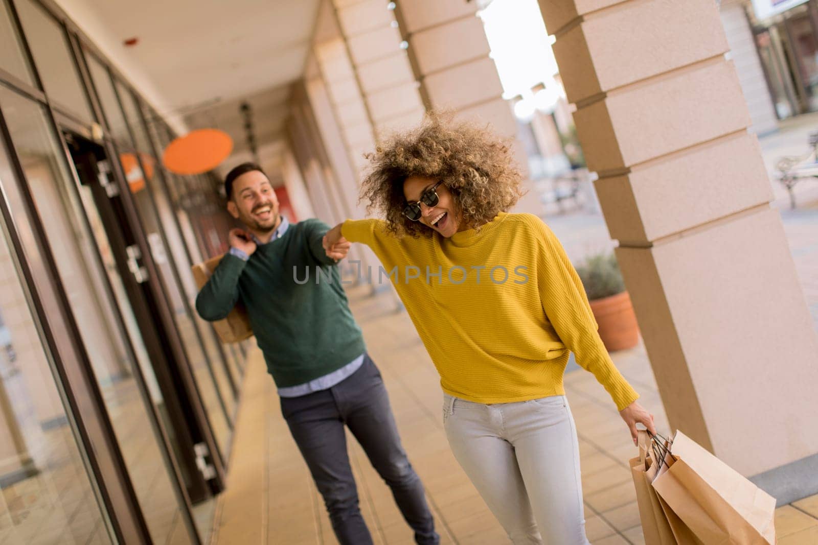Beautiful young multiethnic couple with paper bags enjoying in shopping, having fun in the city