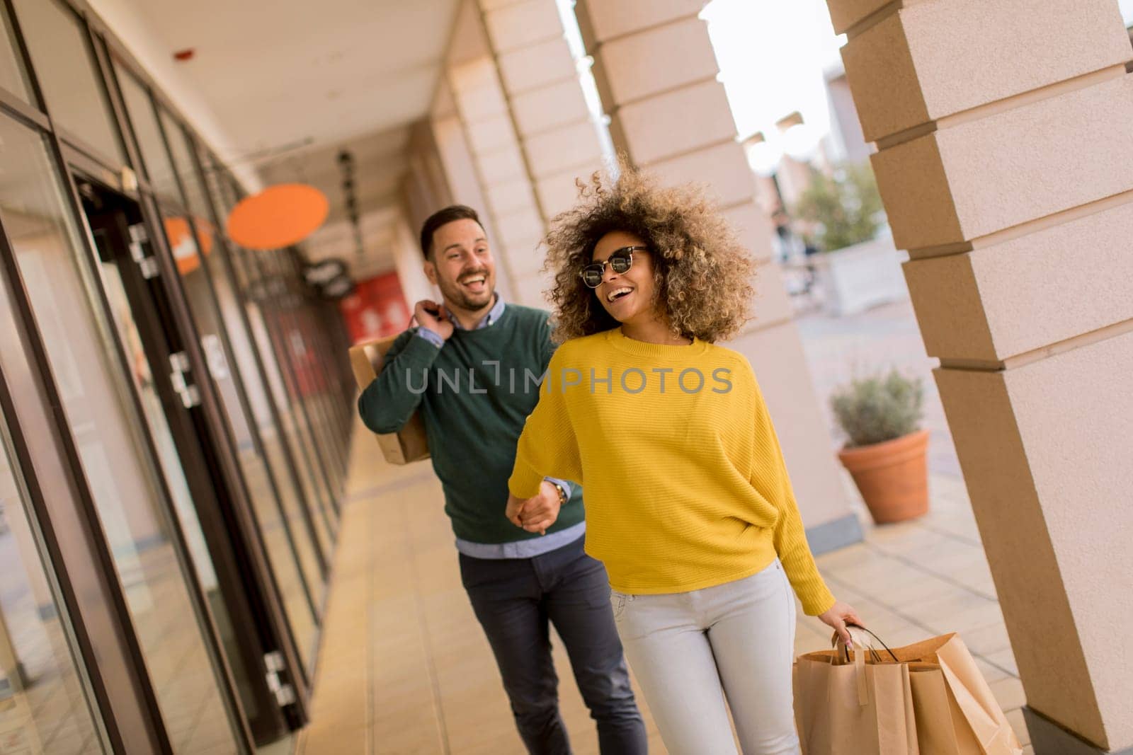 Beautiful young multiethnic couple with paper bags enjoying in shopping, having fun in the city