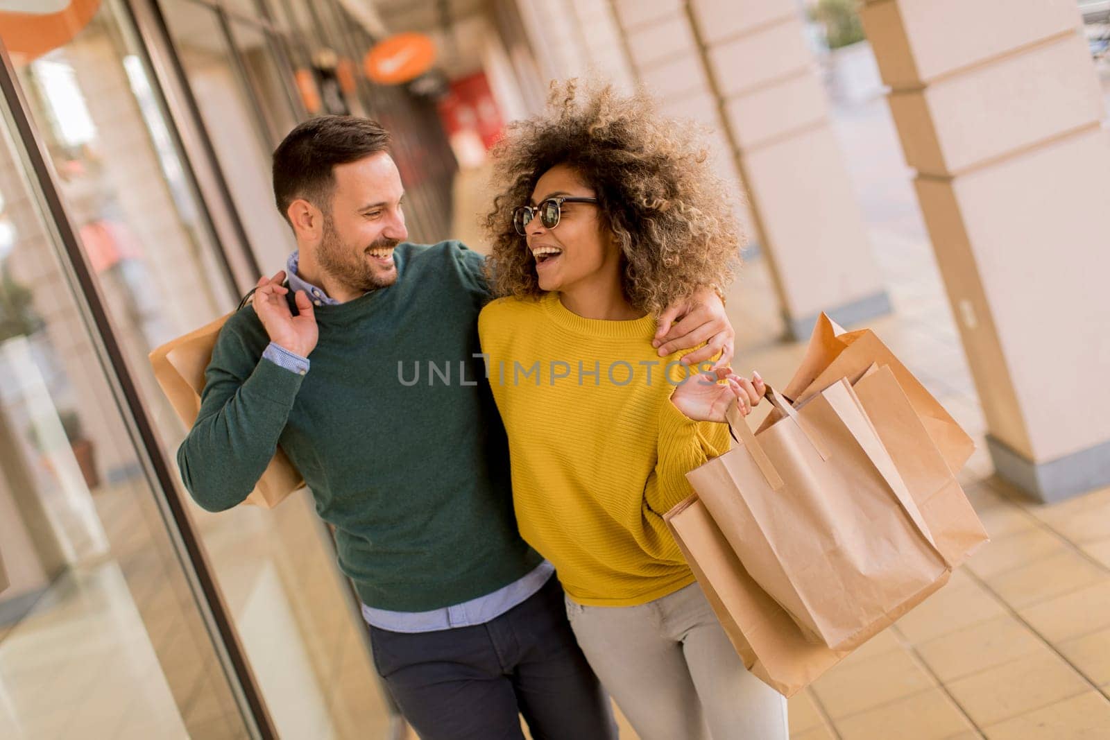 Beautiful young multiethnic couple with paper bags enjoying in shopping, having fun in the city