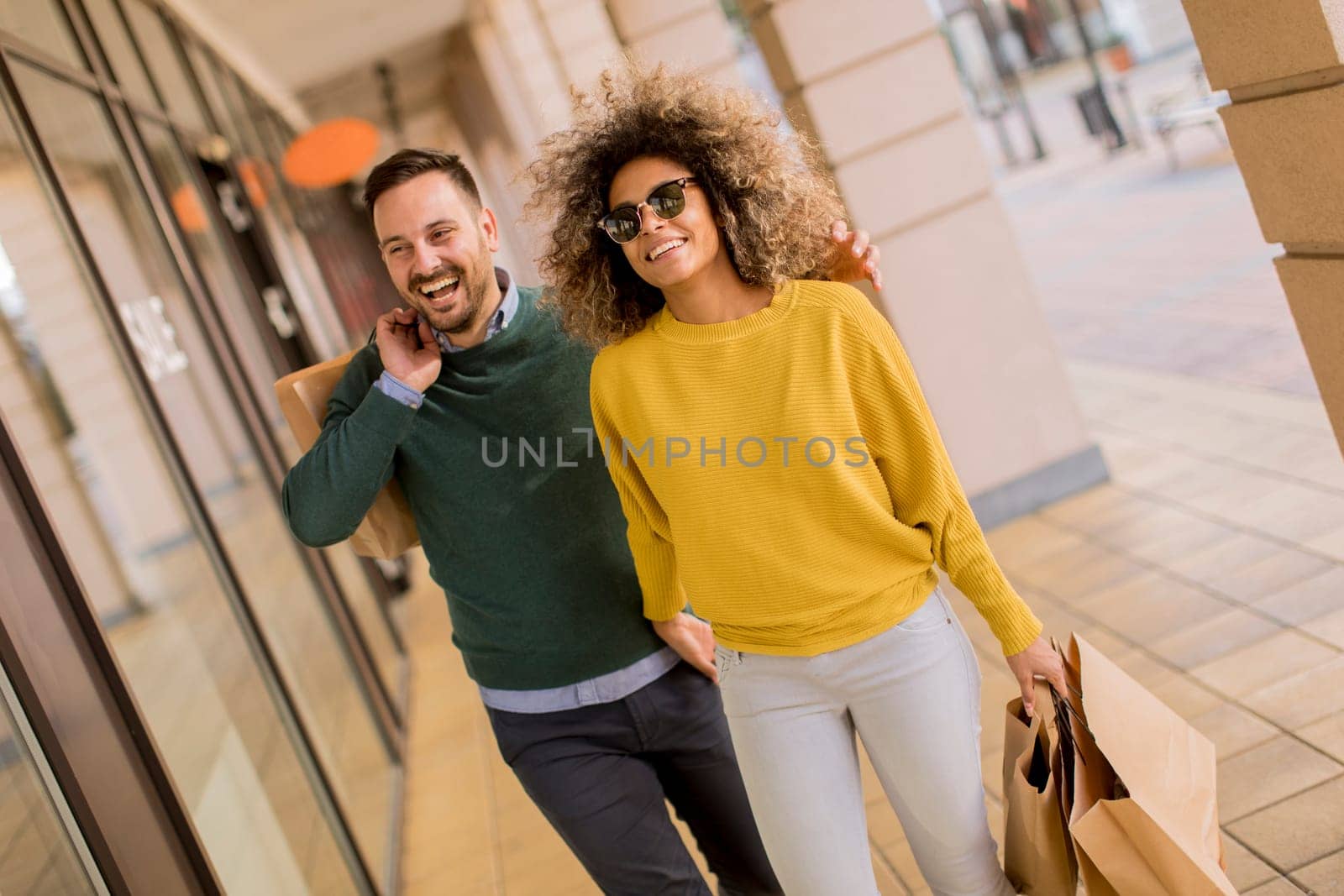 Beautiful young multiethnic couple with paper bags enjoying in shopping, having fun in the city
