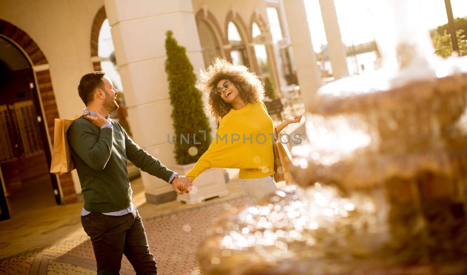 Young multiethnic couple walking by the fountain on a sunny day