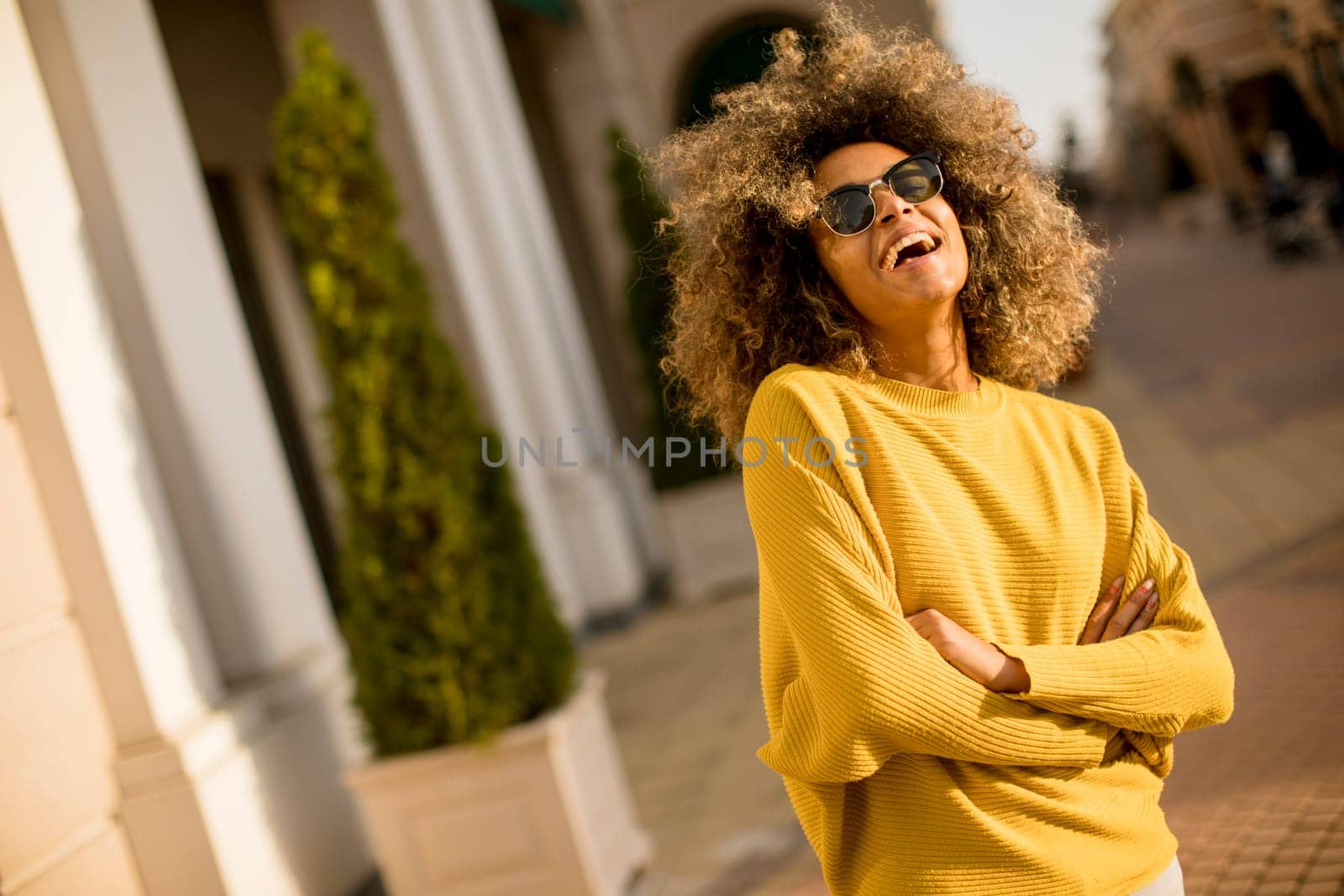 Pretty young black woman with curly hair on the street at sunny day