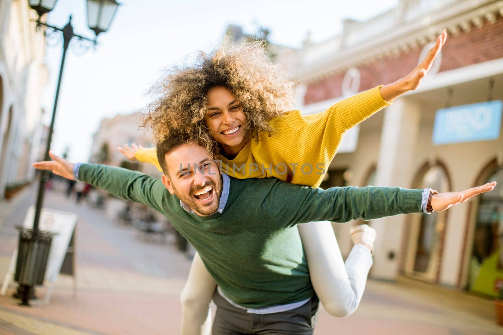 Young man holds a young woman on his back and entertaining themselvs outdoor