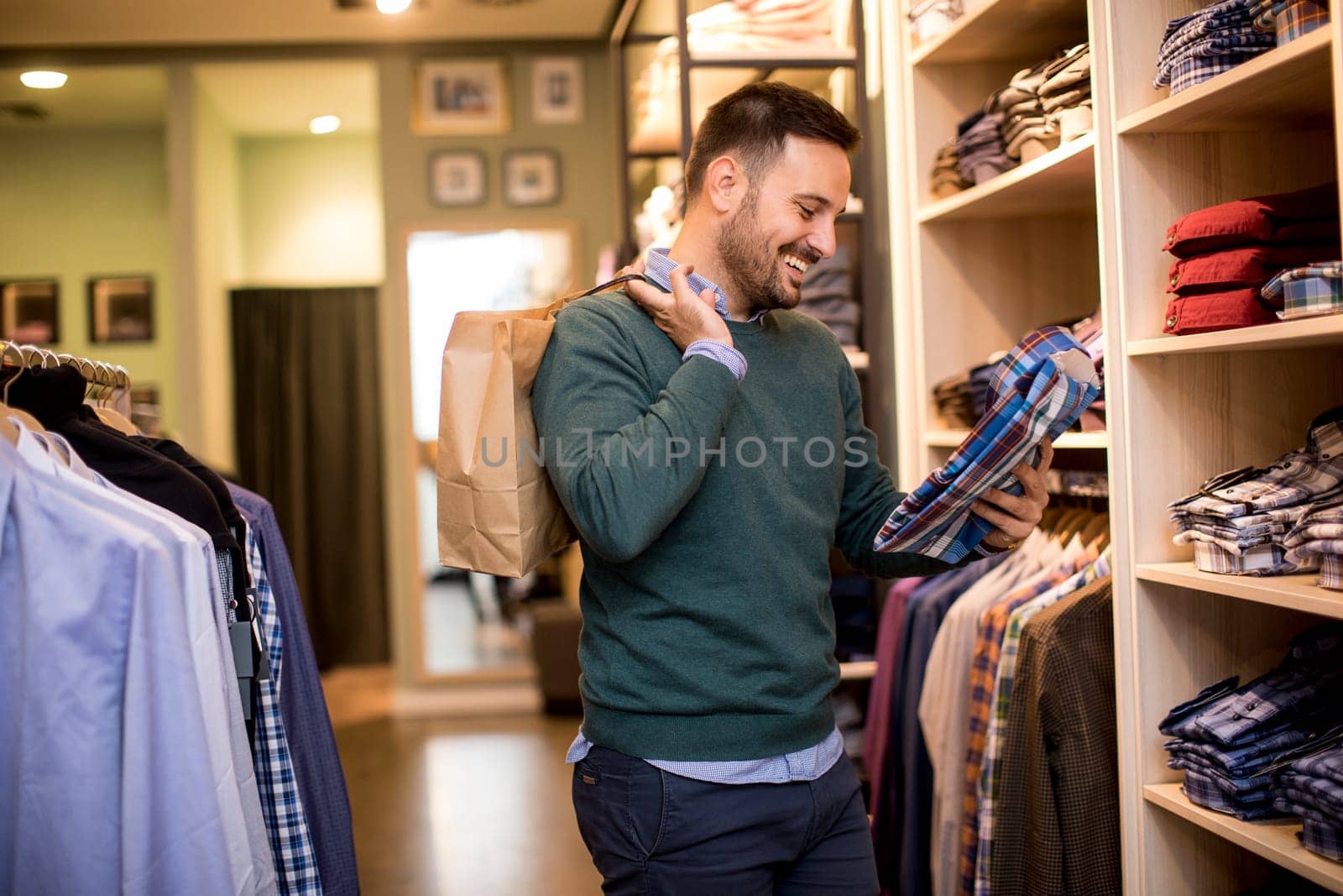 Handsome young man buying shirt in the store