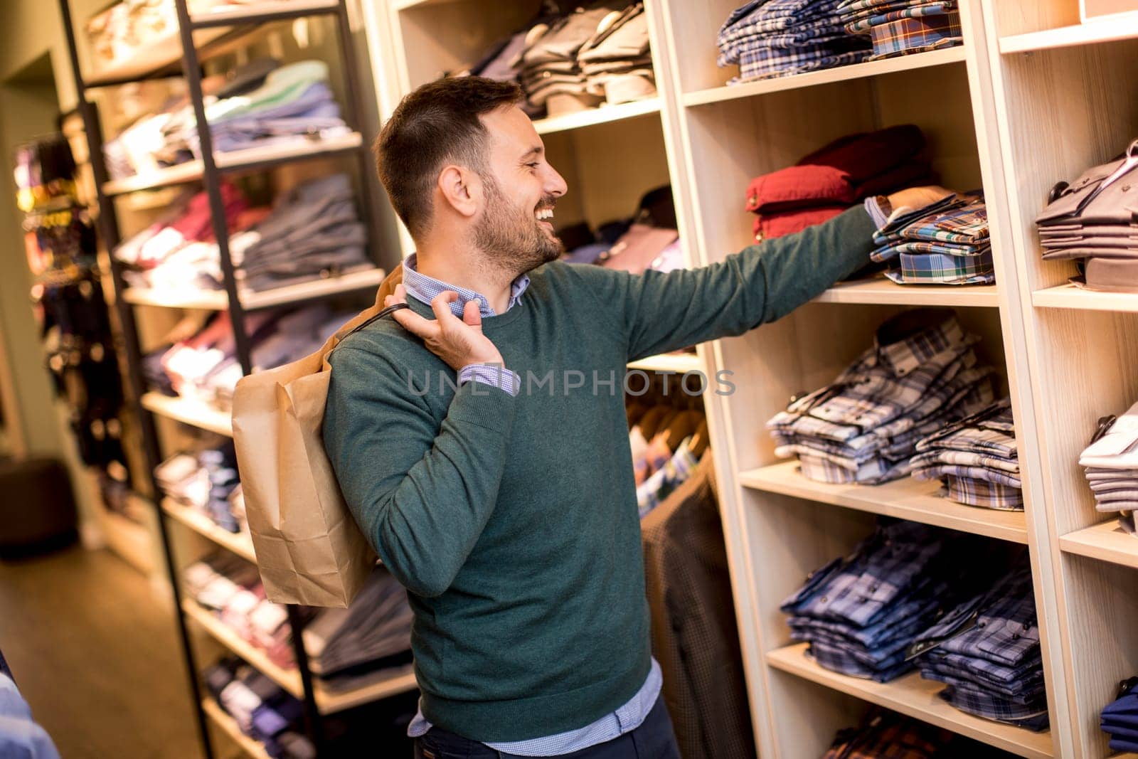 Handsome young man buying shirt in the store
