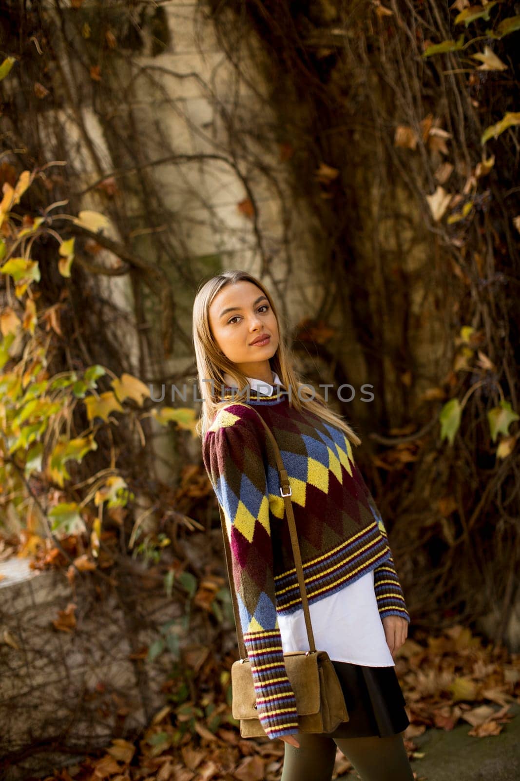 Pretty young woman standing in autumn park