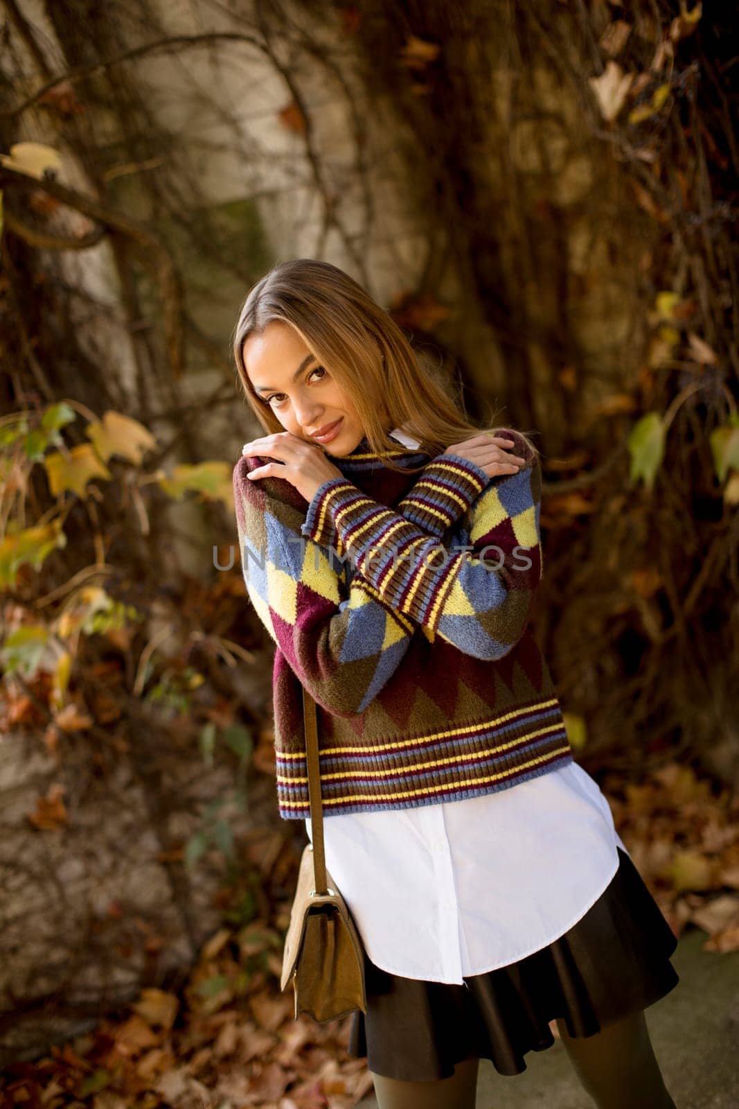 Pretty young woman standing outside at sunny autumn day