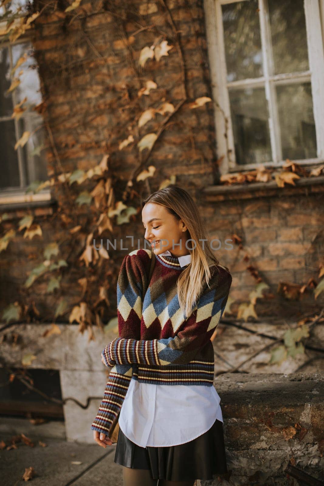 Pretty young woman standing outside at sunny autumn day