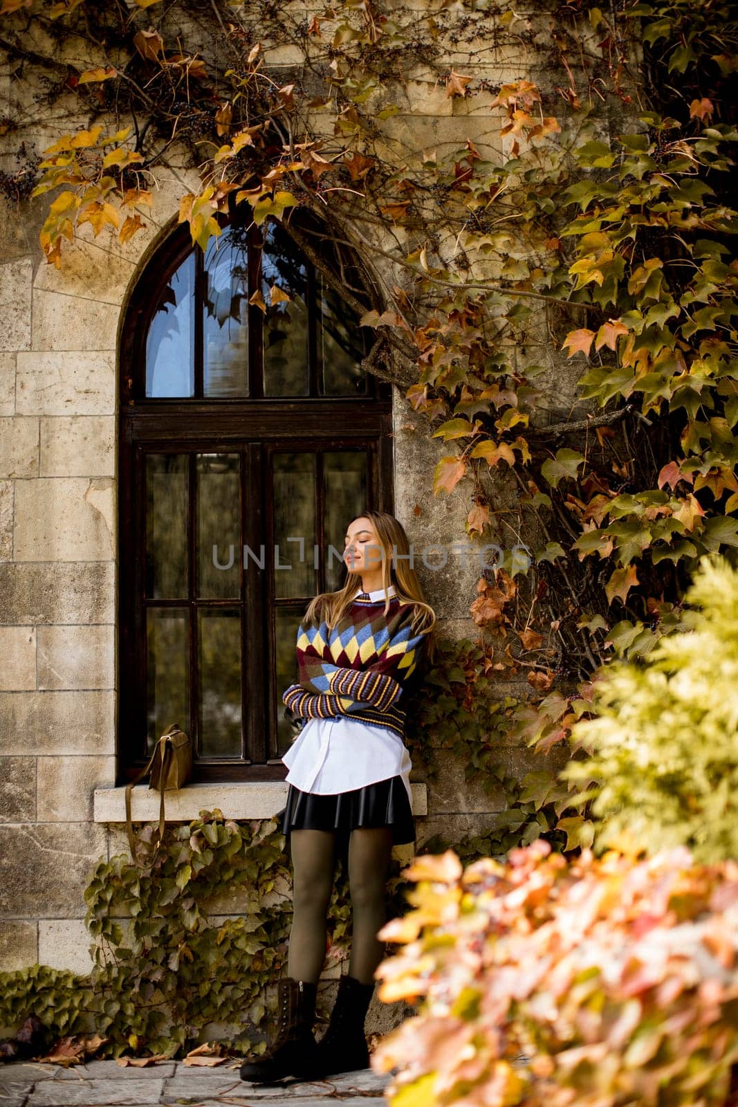 Pretty young woman standing outside at sunny autumn day