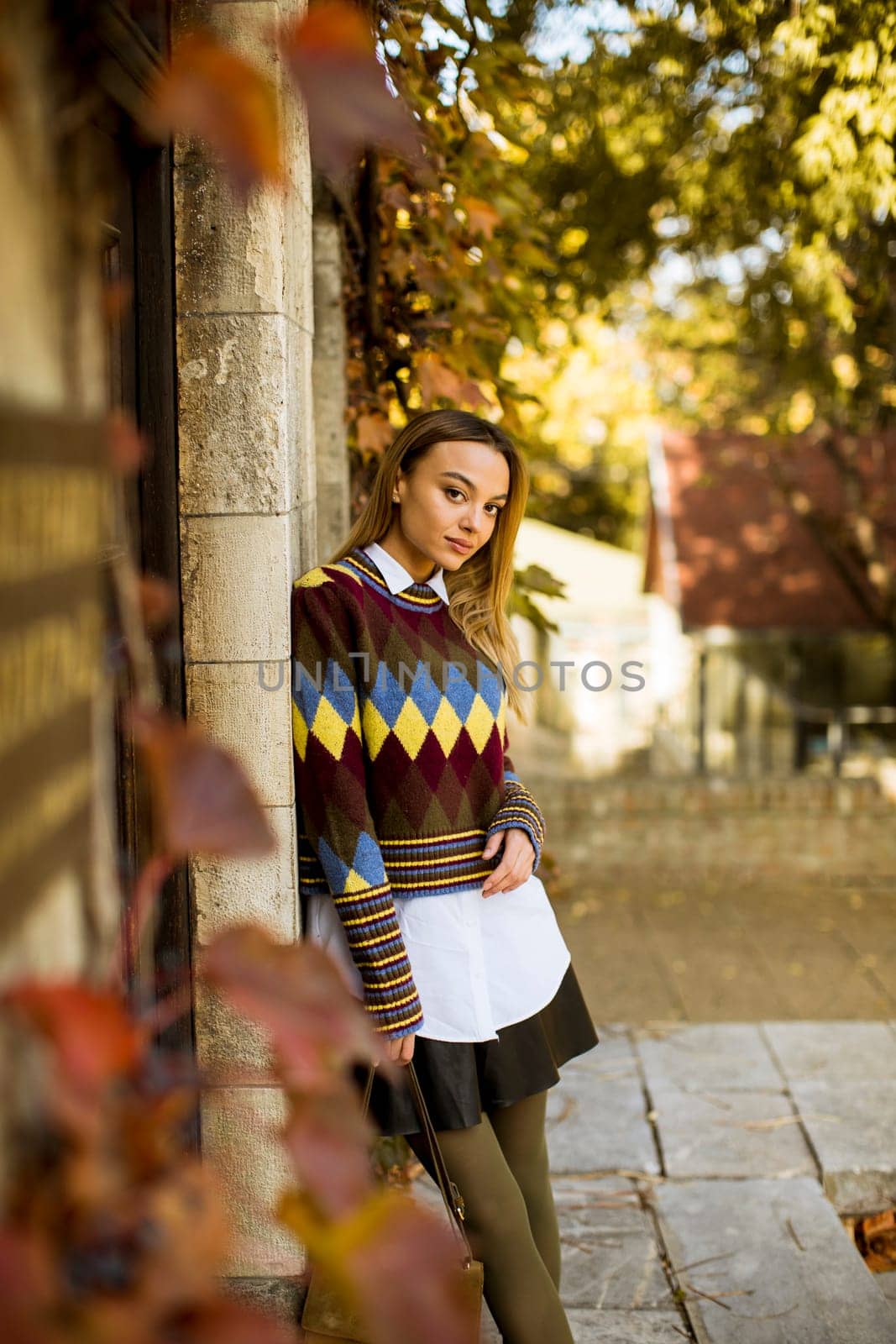 Pretty young woman standing outside at sunny autumn day