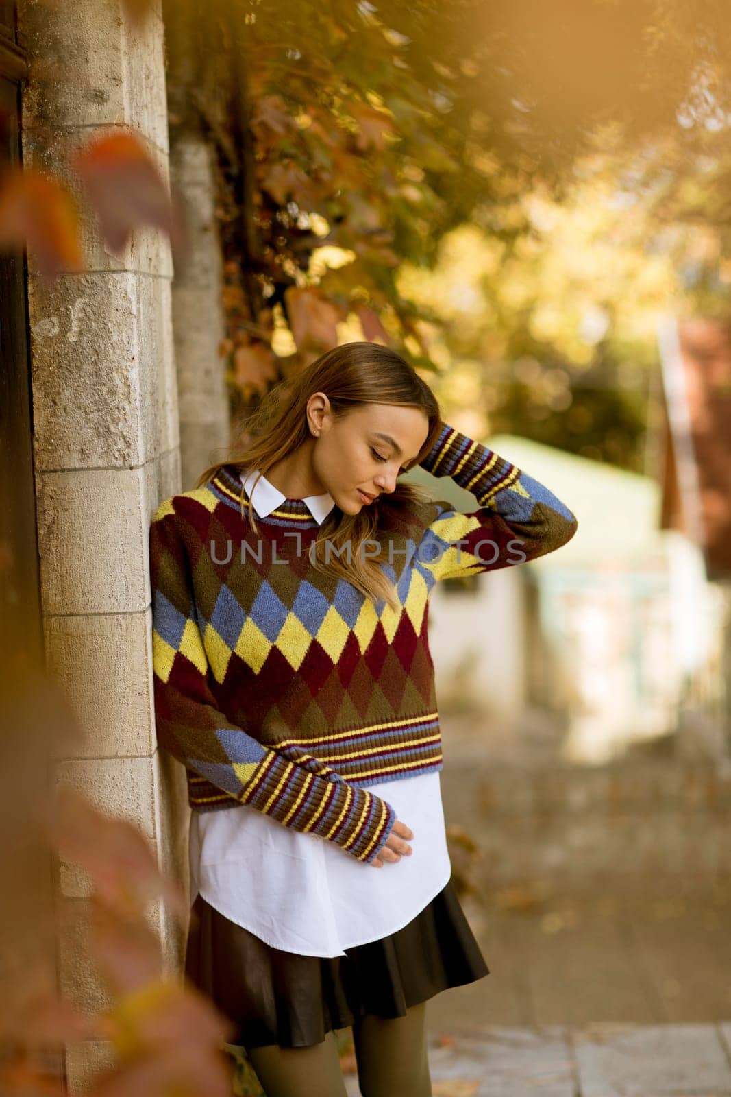 Pretty young woman standing outside at sunny autumn day