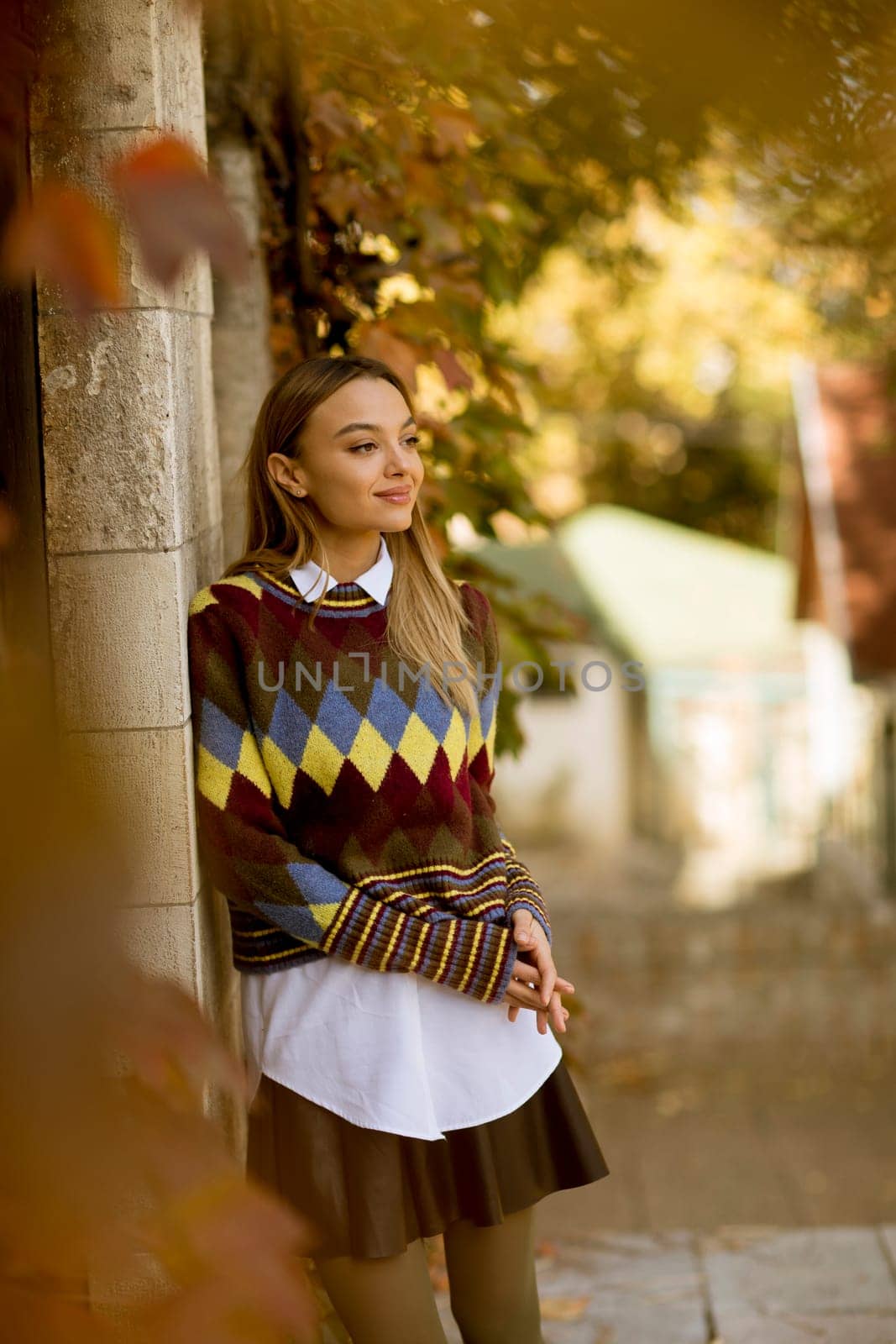 Pretty young woman standing outside at sunny autumn day