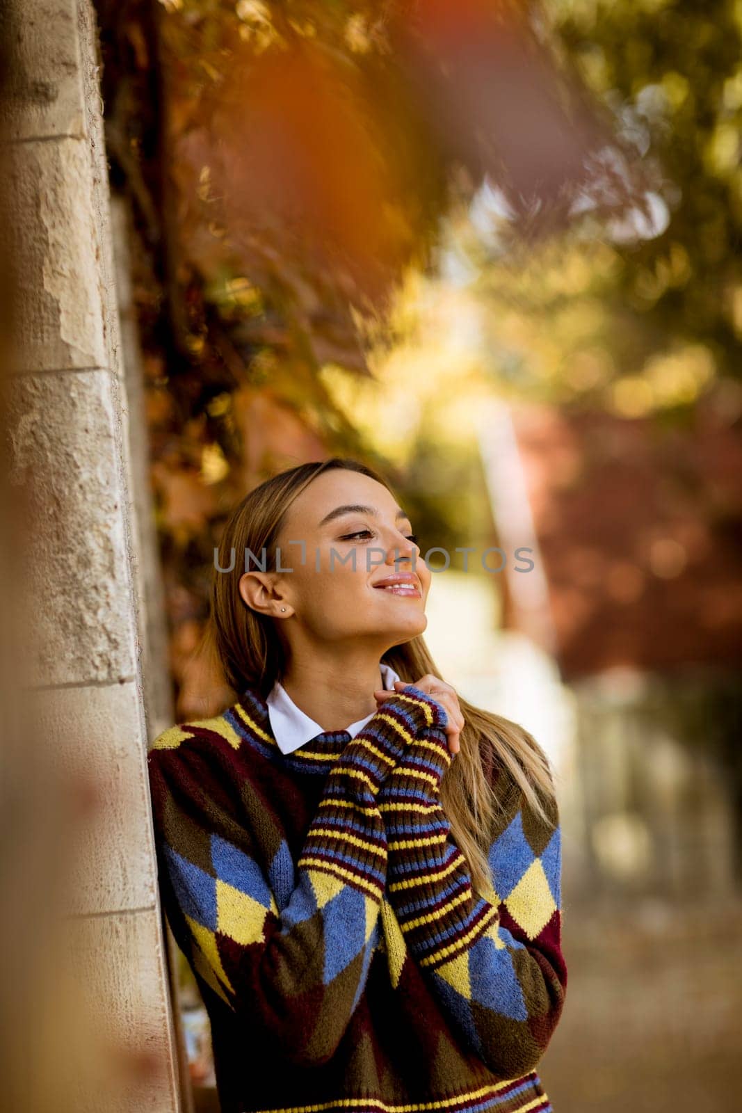 Pretty young woman standing outside at sunny autumn day