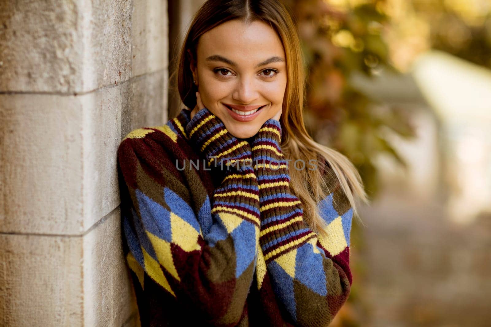 Pretty young woman standing outside at sunny autumn day