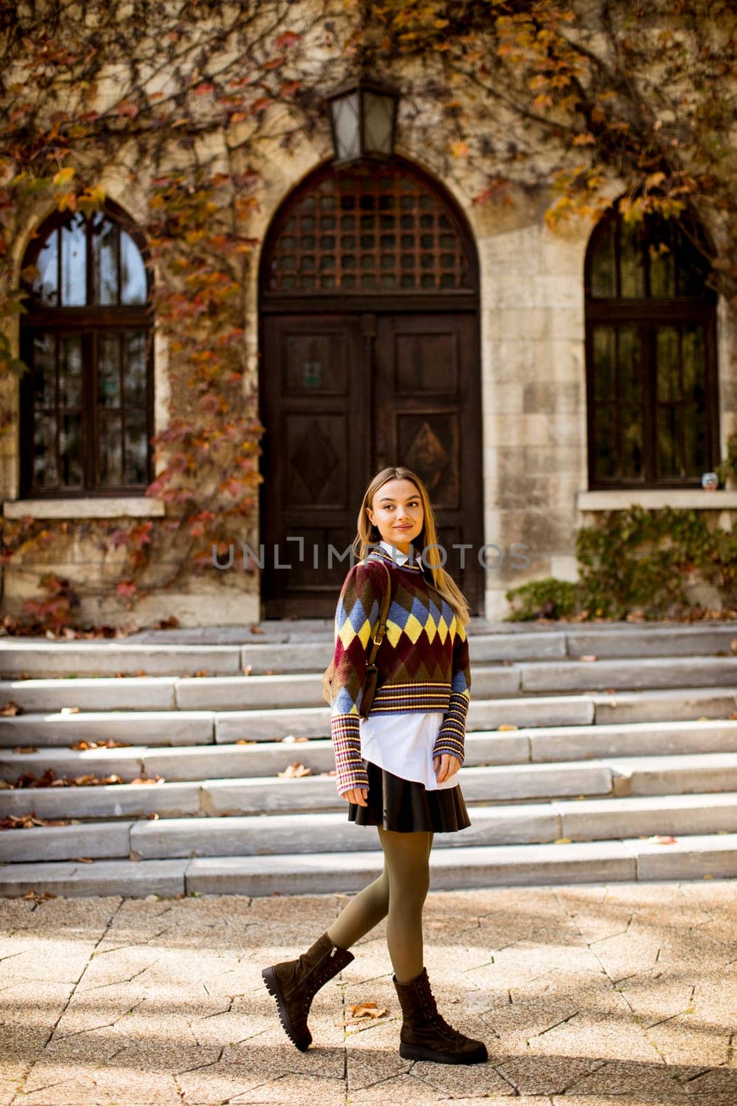 Pretty young woman walking in the autumn park on a sunny day