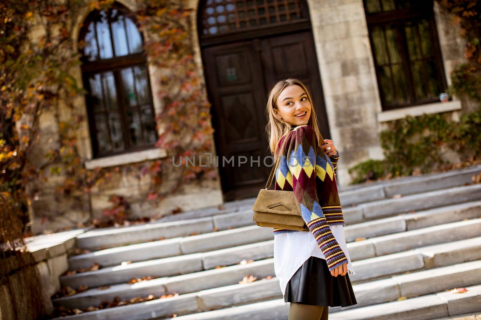 Pretty young woman standing outside at sunny autumn day