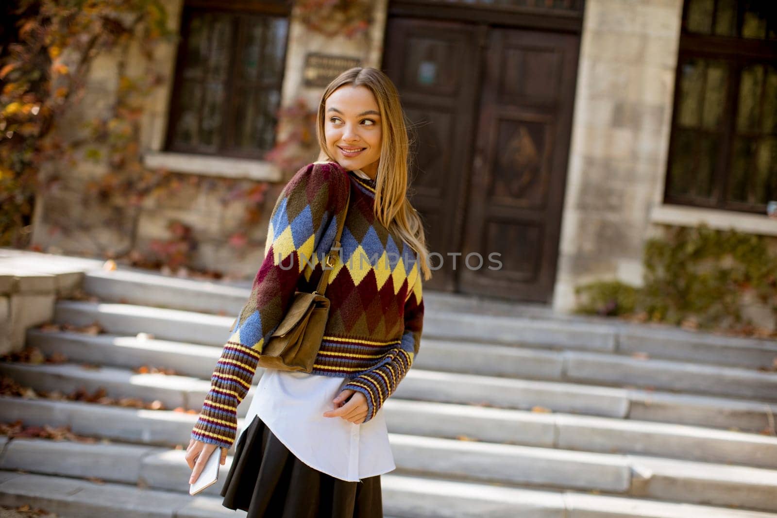 Pretty young woman standing outside at sunny autumn day