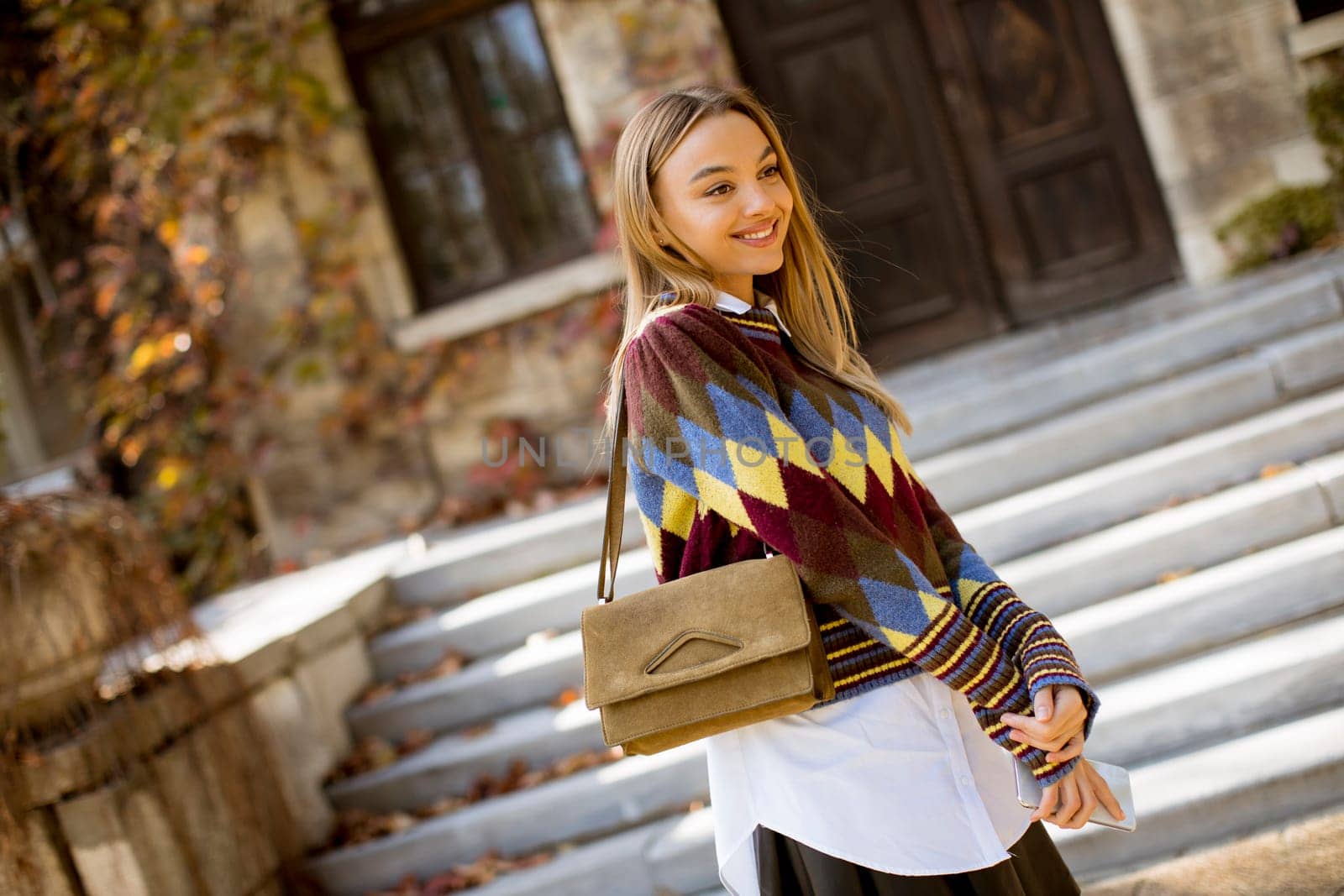 Pretty young woman walking in the autumn park on a sunny day