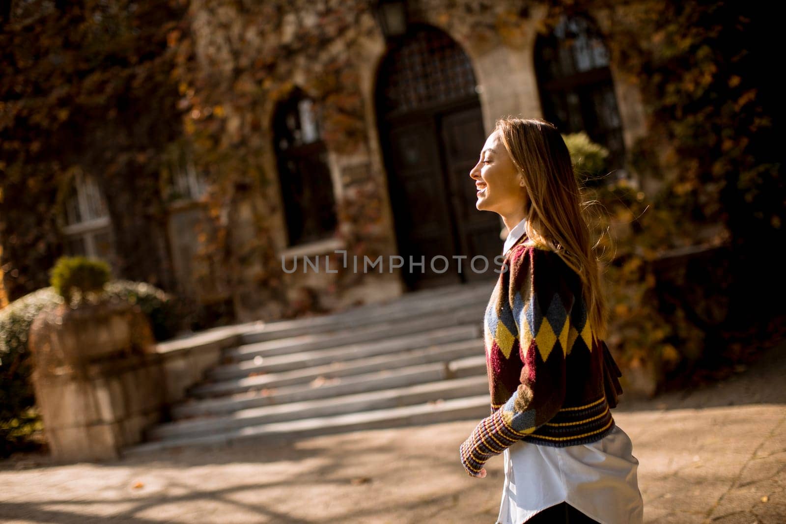 Pretty young woman walking in the autumn park on a sunny day