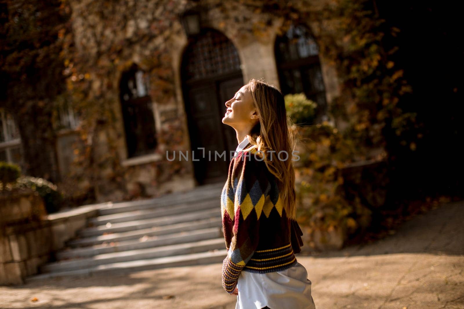 Pretty young woman walking in the autumn park on a sunny day