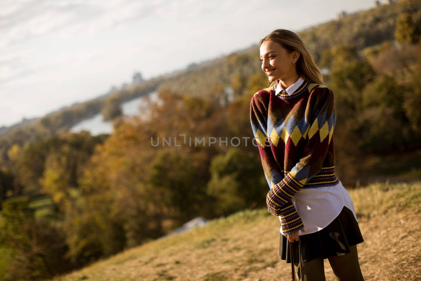 Pretty young woman standing outside at sunny autumn day