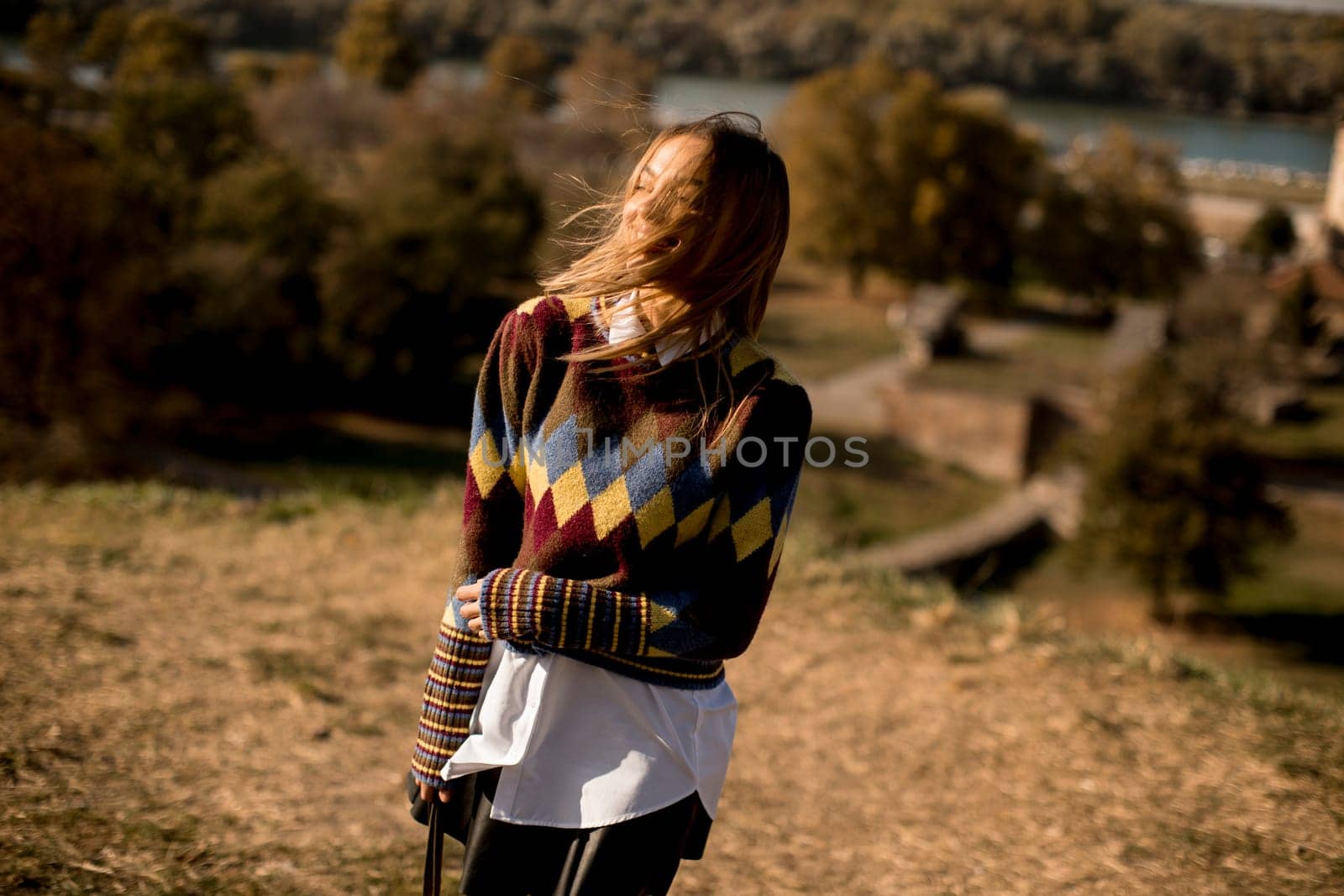 Pretty young woman standing outside at sunny autumn day