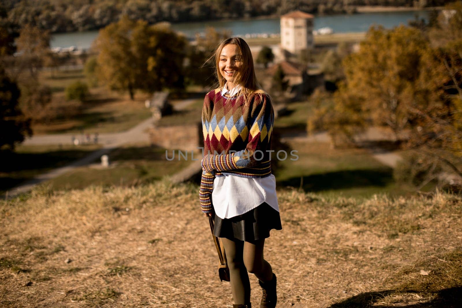 Pretty young woman standing outside at sunny autumn day