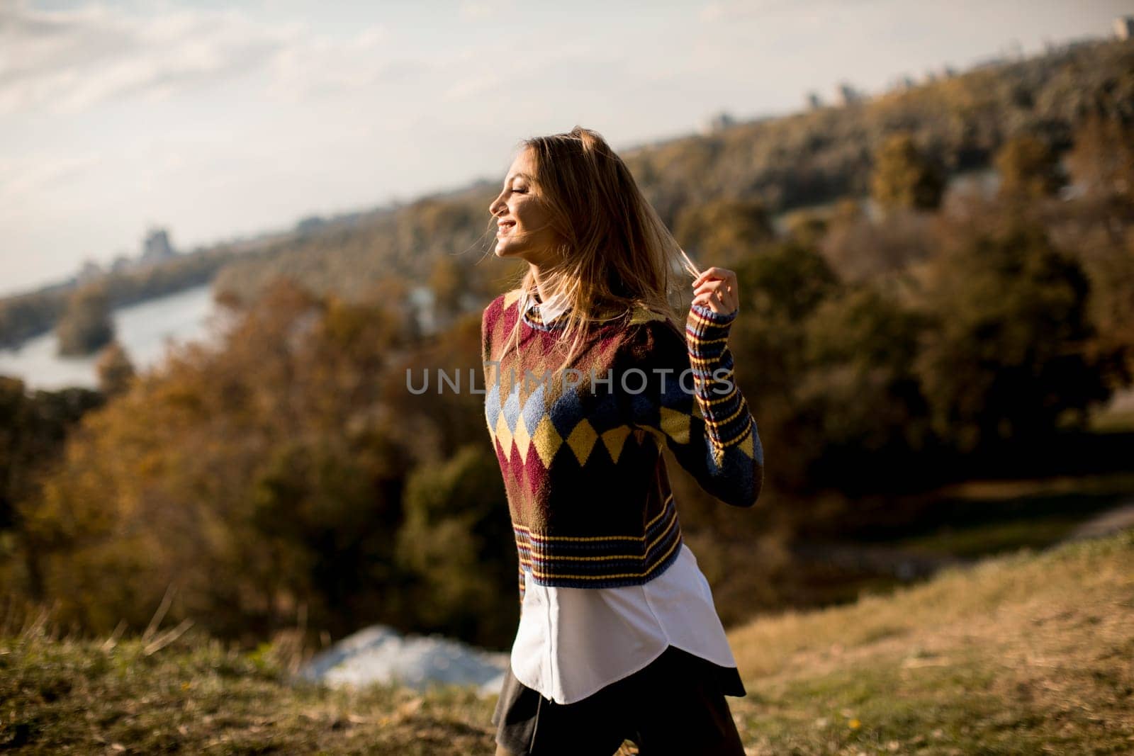 Pretty young woman standing outside at sunny autumn day