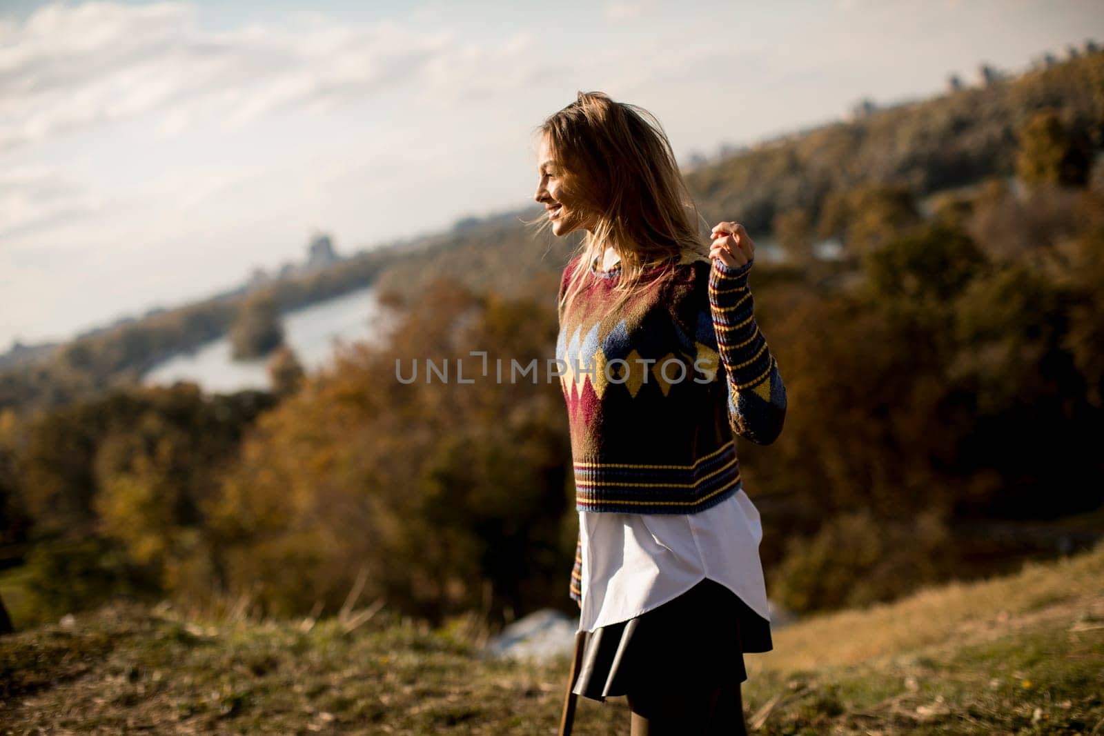 Pretty young woman standing outside at sunny autumn day