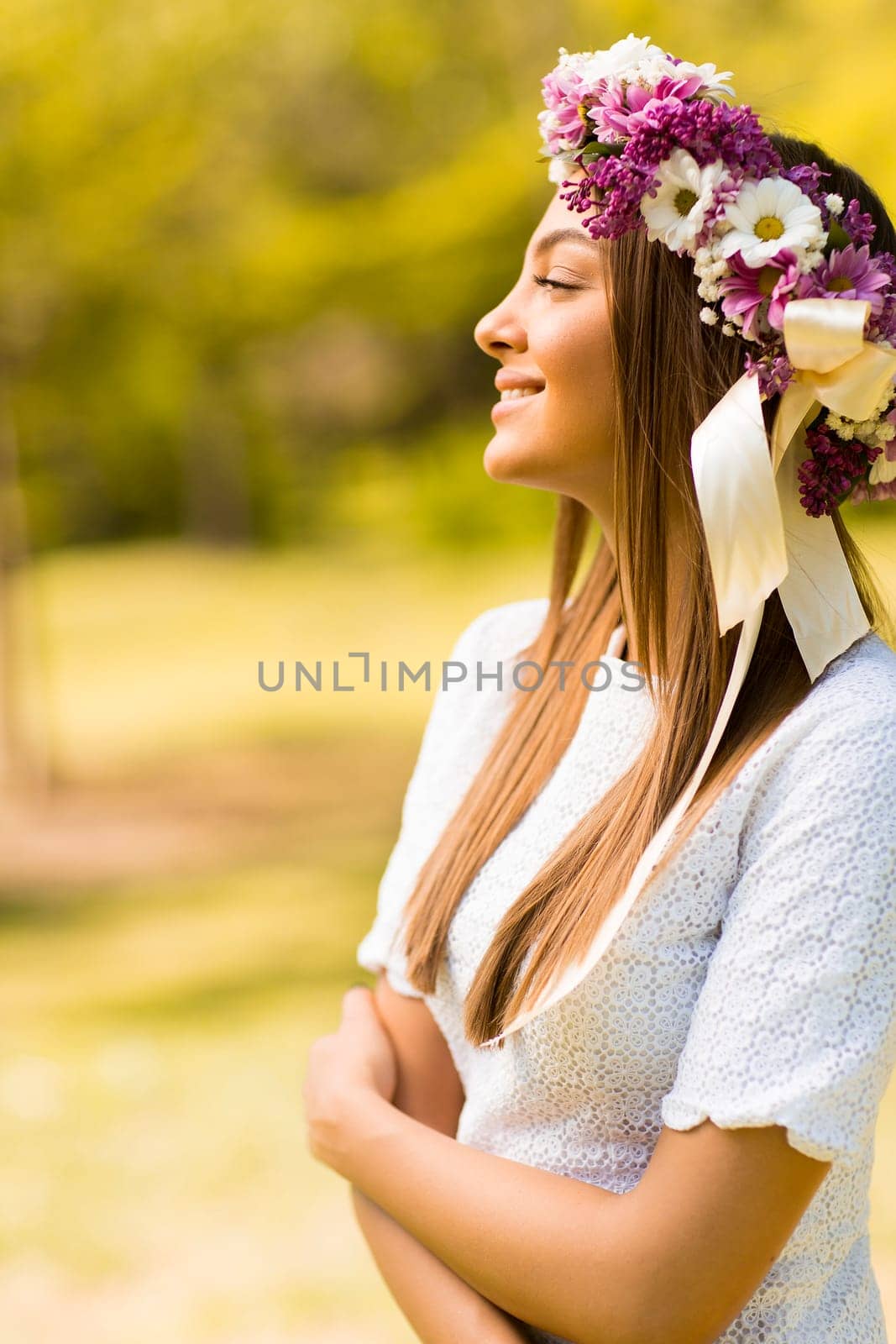Pretty young woman with flowers in her hair on sunny spring day