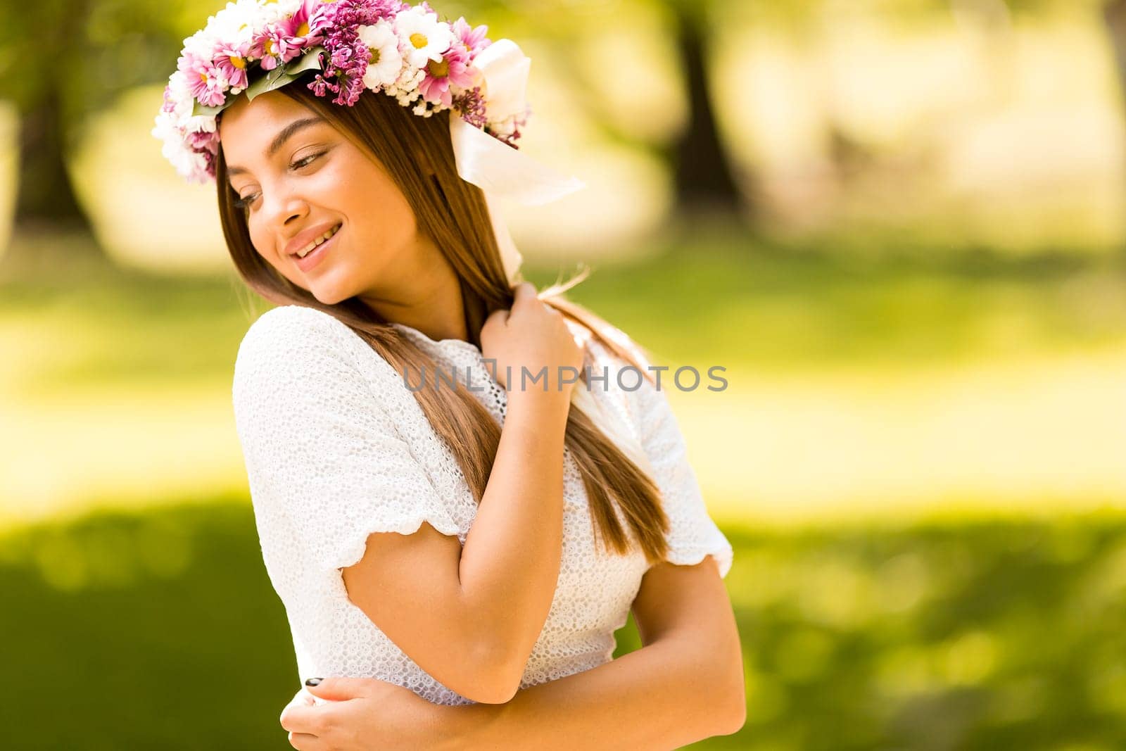 Pretty young woman with flowers in her hair on sunny spring day