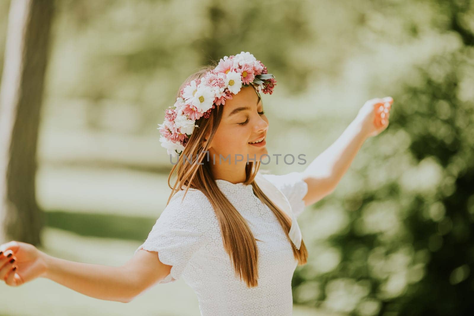 Portrait of young woman with wreath of fresh flowers on head in the park
