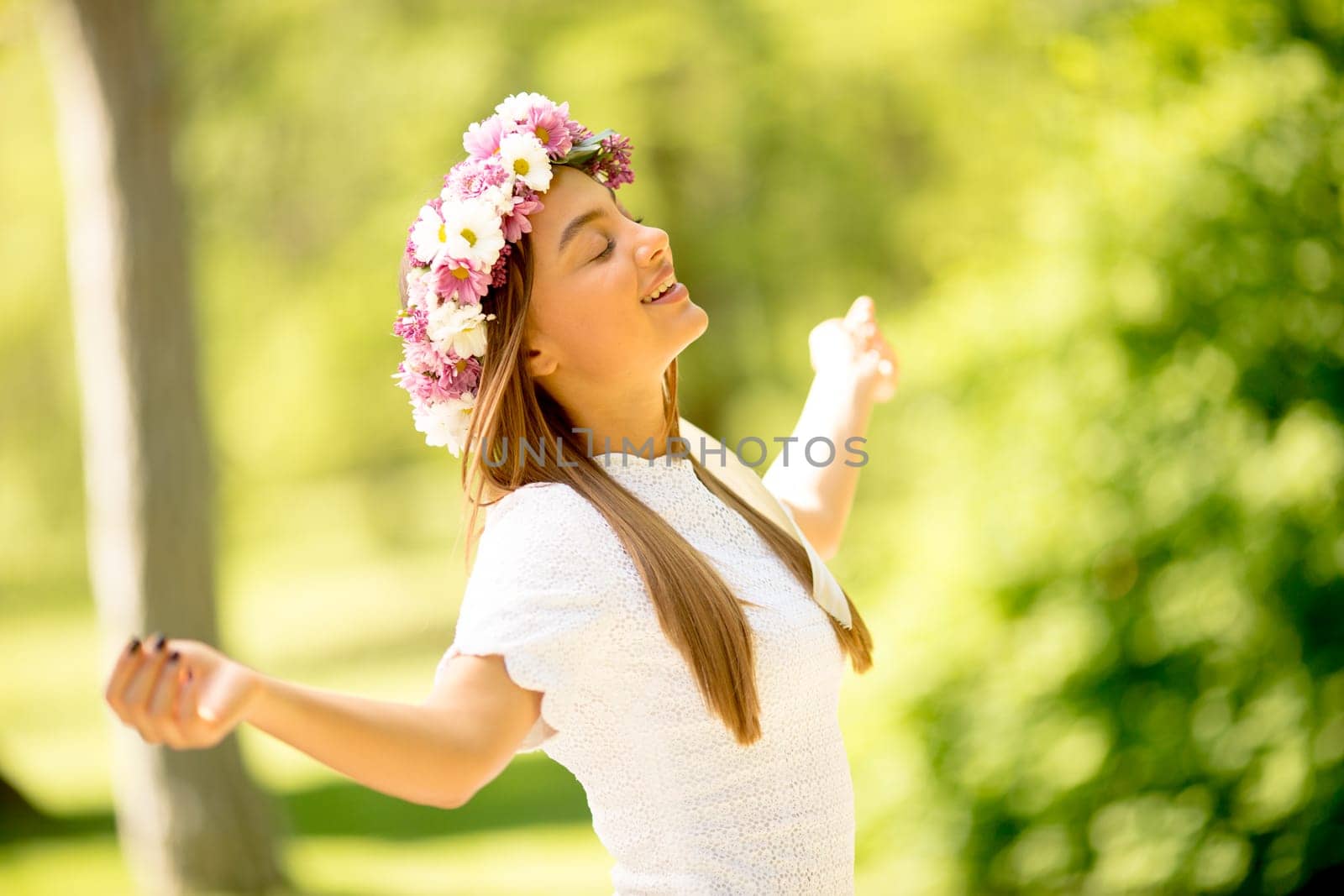 Portrait of young woman with wreath of fresh flowers on head in the park